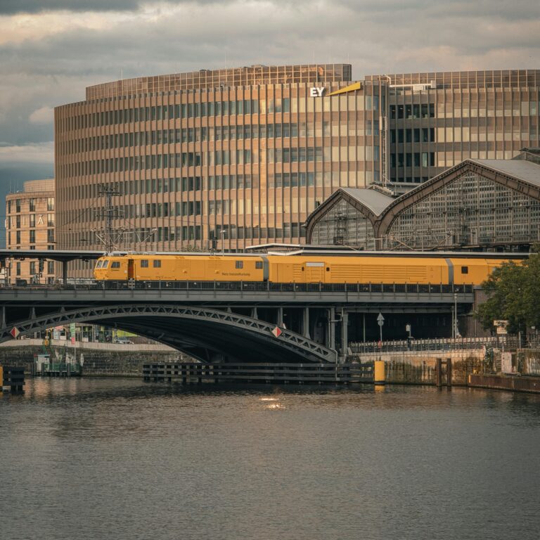 A beautiful view of a yellow train crossing a bridge in Berlin during sunset, showcasing modern architecture.