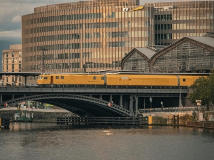 A beautiful view of a yellow train crossing a bridge in Berlin during sunset, showcasing modern architecture.